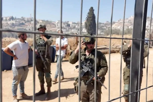 Cumartesi günü işgal altındaki Batı Şeria'nın Ramallah şehri yakınlarındaki Muğayyir köyünde Filistinlilere ait mülklere düzenlenen saldırı sırasında İsrail askerleri ve yerleşimciler (Reuters)