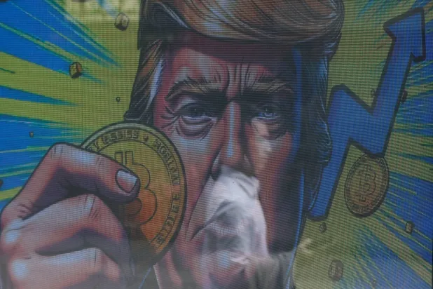 رسم توضيحي يظهر دونالد ترمب وهو يحمل عملة بتكوين معروض خارج متجر لتداول العملات المشفرة في هونغ كونغ بالصين (رويترز)