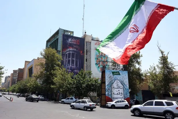 Iranians drive past an anti-US billboard featuring pictures of US President Donald Trump and his family on top of US flag-draped coffins, accompanied by a sentence in Persian that reads "Blood for Blood," that hangs at Palestine Square in Tehran, Iran, 16 July 2026. (EPA)