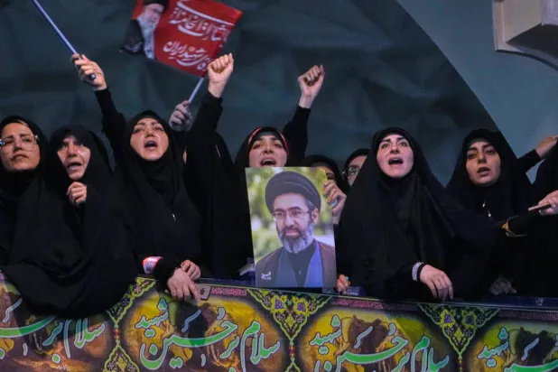 Mourners chant slogans as one of them holds a poster of the Supreme Leader, Mojtaba Khamenei, in a ceremony commemorating the late Supreme Leader, Ali Khamenei, in Tehran, Tuesday, July 14, 2026. (AP Photo/Vahid Salemi)