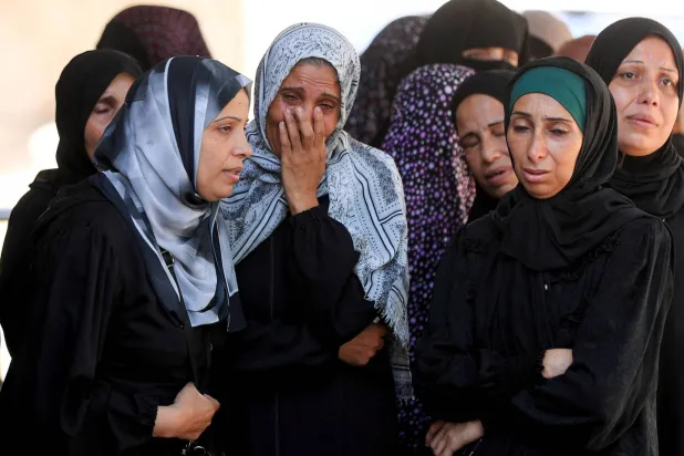 فلسطينيات يبكين يوم الأحد خلال جنازة ضحايا غارة إسرائيلية على مدينة غزة (رويترز)