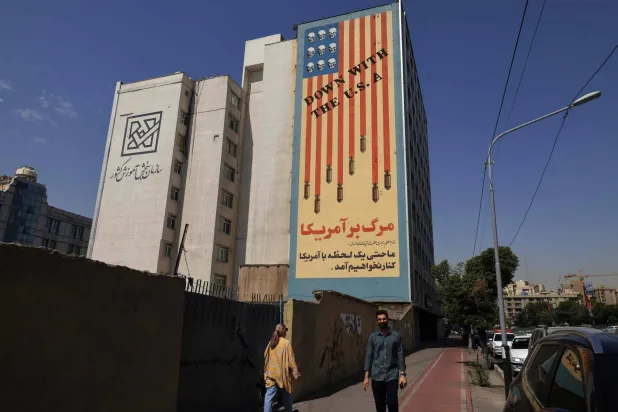 Iranians walk past an anti-US banner in Tehran on July 19, 2026. (AFP)