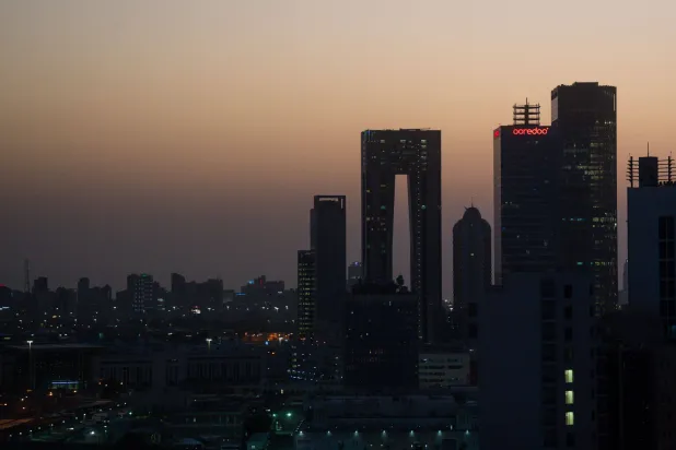 06 October 2025, Kuwait, Kuwait City: The rising sun colors the sky behind the skyline of Kuwait City reddish. (dpa)