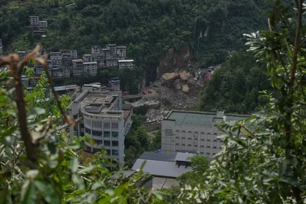 Rescuers use a heavy duty machine to clear rubble to search for trapped victims at the scene of a landslide in Pengshui County in southwestern China's Chongqing on Sunday, July 19, 2026. (AP)