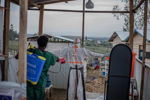 Doğu Kongo'nun Ituri eyaletindeki Rwanpara Ebola tedavi merkezinde, bir uzman doktor hasta bakım ünitesinden ayrılırken doktoru dezenfekte ediyor (AFP)