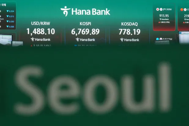 شاشات تعرض مؤشر «كوسبي» وسعر صرف العملات الأجنبية بين الدولار والوون الكوري الجنوبي في غرفة تداول بنك هانا بسيول (أ.ب)