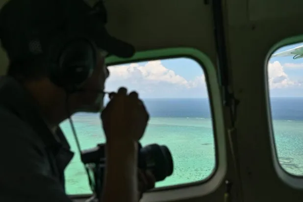 A Philippine Coast Guard personnel talks on a mic as he looks over Scarborough Shoal in the disputed South China Se. Jam STA ROSA / AFP

