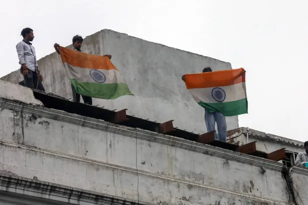 People hold Indian national flags on top of a building in New Delhi, India, 20 July 2026. EPA/RAJAT GUPTA