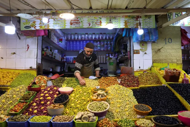 صاحب متجر يفرز الزيتون داخل سوق شعبية في مدينة الدار البيضاء المغربية (رويترز)