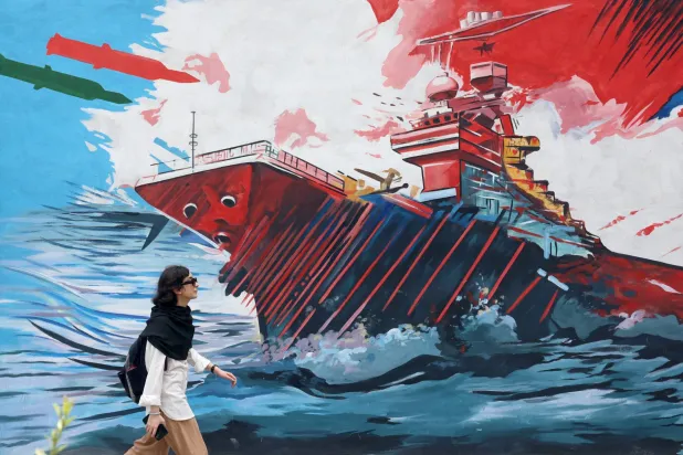 A woman walks next to anti-US graffiti on a street in Tehran, Iran, 20 July 2026. EPA/ABEDIN TAHERKENAREH