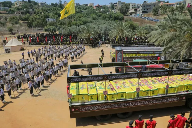 نعوش عناصر «حزب الله» الذين قُتلوا خلال اشتباكات مع الجيش الإسرائيلي إلى جانب نعش رمزي للمرشد الإيراني السابق علي خامنئي... وذلك في أثناء جنازة جماعية بقرية مجدل سلم بجنوب لبنان يوم 18 يوليو 2026 (أ.ف.ب)