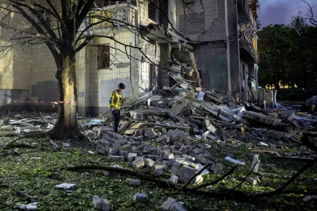 Kurtarma görevlisi, Rusya'nın Ukrayna'ya yönelik saldırısı sırasında Kiev'de Rus füze saldırılarıyla hasar gören bir apartman binasının enkazı arasında yürüyor (Reuters)