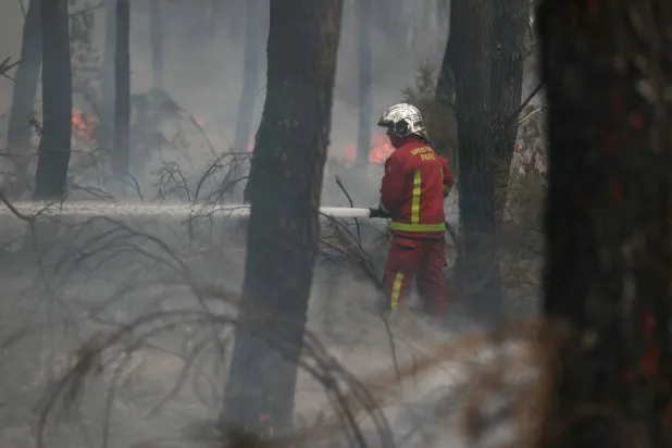 A firefighter of Paris Fire Brigade douses the hotspots in Marcheprime west of Bordeaux on July 26, 2026 as a wildfire has been ravaging the forest north of the Arcachon Basin (Gironde) since July 22. (Photo by Alain JOCARD / AFP)