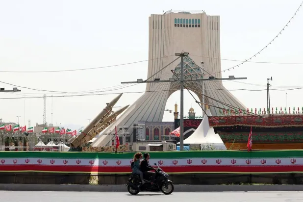 An Iranian couple rides a motorbike next to Iranian missiles, Zolfaghar, on display at Azadi Square in Tehran, Iran, 24 July 2026. (EPA)