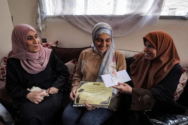 Palestinian high school student Saba Rabah (C), the top-ranked student in the science stream of the Palestinian national high school exams, celebrates with family at the Al-Maghazi camp for Palestinian refugees in the central Gaza Strip on July 26, 2026. (AFP)