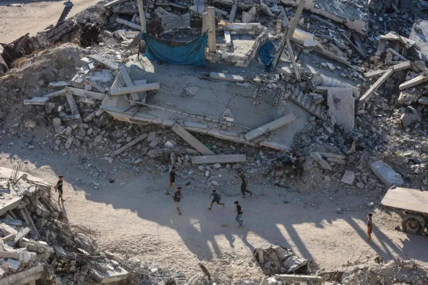 Pazartesi günü Gazze şehrinde yıkılmış binaların arasında top oynayan çocuklar (AFP)