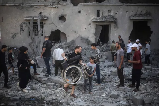 Gazze Şeridi’nin orta kesimindeki Deyr el-Balah’ta bir önceki gece İsrail hava saldırıları sonucu hasar gören ve yıkılan binaları inceleyen Filistinliler (AFP)