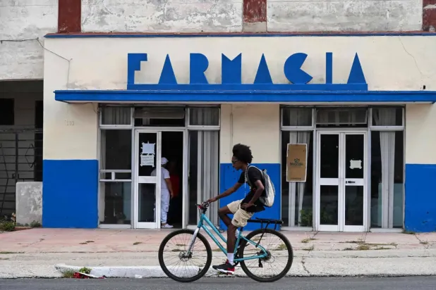 Havana'da bisikletiyle bir eczanenin önünden geçen adam, (AFP)
