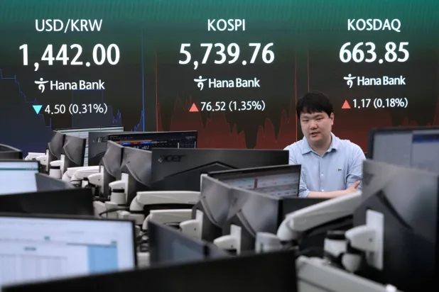 يمر متداول عملات أمام شاشة تعرض مؤشر «كوسبي» وسعر صرف الدولار الأميركي مقابل الوون في بنك هانا في سيول (أ.ب)