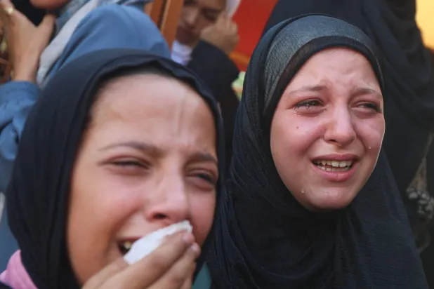 فتاتان تنتحبان خلال جنازة فلسطينيين قُتلوا في غارات إسرائيلية استهدفت خياماً في خان يونس جنوب غزة (رويترز)