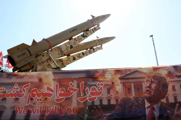 صواريخ «ذو الفقار» الإيرانية معروضة فوق لافتة تتوعد بقتل الرئيس الأميركي دونالد ترمب في ساحة آزادي بطهران الخميس (إ.ب.أ)