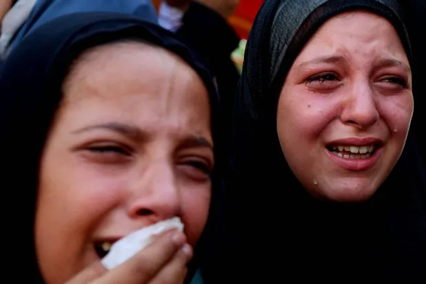  فتاتان تنتحبان أمس خلال جنازة فلسطينيين قُتلوا في غارات إسرائيلية استهدفت خياماً في خان يونس جنوب غزة (رويترز)