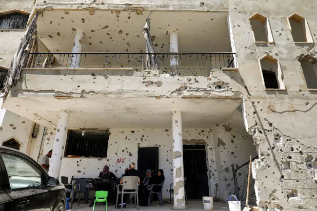 31 July 2026, Lebanon, Zawtar Al-Gharbieh: A Lebanese family sit in the shadow of their bullet riddled and shell-pocked building in the southern Lebanese village of Zawatar al-Gharbieh. Photo: Marwan Naamani/ZUMA Press Wire/dpa