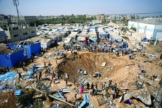 
فلسطينيون يعاينون مكاناً استهدفته ضربة جوية إسرائيلية قرب مستشفى الأقصى بدير البلح وسط قطاع غزة أمس (أ.ب)