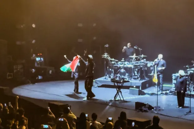 Robert Del Naja and Grant Marshall from Massive Attack stand with a Palestinian flag onstage at the end of their performance in Singapore, July 29, 2026, in this screengrab from video obtained from social media. (Simran Panaech/via Reuters)