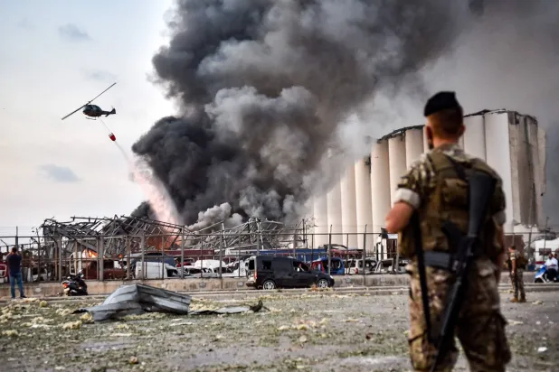 Lebanese army soldiers stand while behind a helicopter puts out a fire at the scene of an explosion at the port of Lebanon's capital Beirut on August 4, 2020. (AFP)