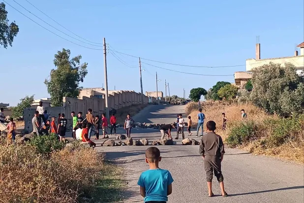 أطفال يغلقون الطريق في قرية عابدين بمنطقة حوض اليرموك بريف درعا الغربي جنوب سوريا في محاولة لمنع دوريات الجيش الإسرائيلي من التوغل في القرية (فيسبوك)