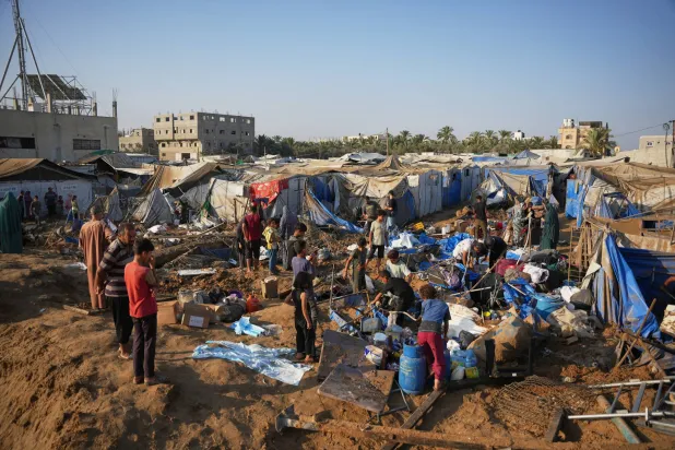 فلسطينيون يتفقّدون موقع غارة جوية إسرائيلية في دير البلح بقطاع غزة يوم 1 أغسطس 2026 (أ.ب)
