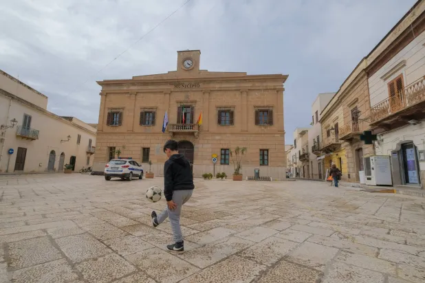A boy plays football outside Favignana's municipal building in Favignana, Italy, May 5, 2021. (Reuters)