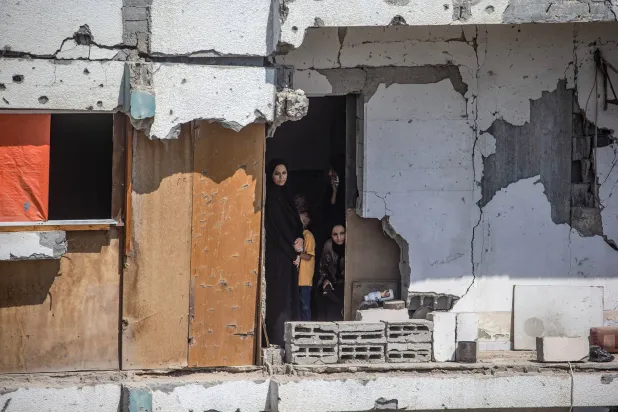فلسطينيون يشاهدون جنازة 112 من أفراد عشيرتهم شرق مدينة غزة بعد انتشالهم من تحت أنقاض مباني دمرت في 2023 (إ.ب.أ)