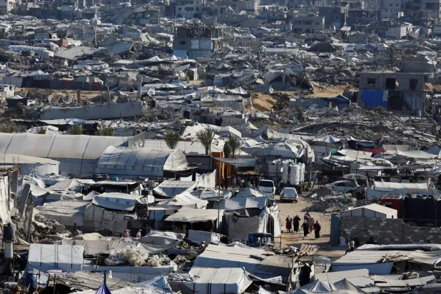 Filistinliler, Gazze Şeridi'nin kuzeyindeki Cibaliye mülteci kampında savaş sırasında yıkılan konut binalarının enkazı arasında yürüyor (Reuters)