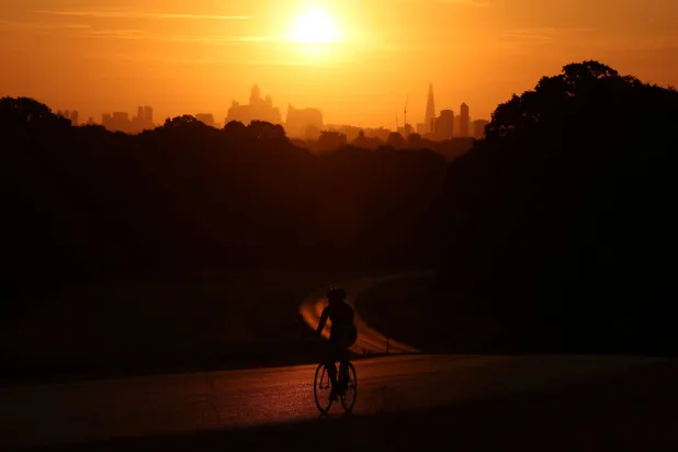 A cyclist rides shortly after sunrise as an amber heat health alert comes into effect and after Britain’s Environment Agency declared seven areas of England to be in drought, in Richmond Park, London, Britain, August 3, 2026. REUTERS/Toby Melville