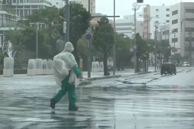  In this image made from video provided by NTV-NNN, a person walks in the rain as typhoon Dolphin approaches the city, in Naha, Japan, Friday, Aug. 7, 2026. (NTV-NNN via AP) 