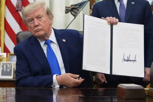 الرئيس الأميركي دونالد ترمب يرفع قراراً تنفيذياً في البيت الأبيض يوم 6 أغسطس (أ.ب)