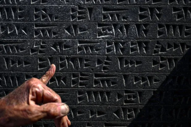 Kusman runs his finger over a tablet engraved with the ancient Urartu language. Ozan KOSE / AFP
