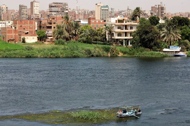 A fisherman travels on a boat with his family during low water levels on the River Nile with crowded residential buildings in the capital city of Cairo, Egypt, August 3, 2026. REUTERS/Amr Abdallah Dalsh