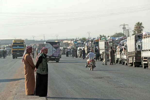 Onlookers stand along the road as Syrian Kurds, who were living in displacement camps in the city of Hasakeh, prepare to head back to the northeastern border town of Ras al-Ain on August 10, 2026. (AFP)