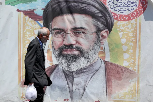 إيراني يمر أمام صورة للمرشد مجتبى خامنئي في طهران غداة توقيع اتفاق إنهاء الحرب مع الولايات المتحدة (إ.ب.أ)