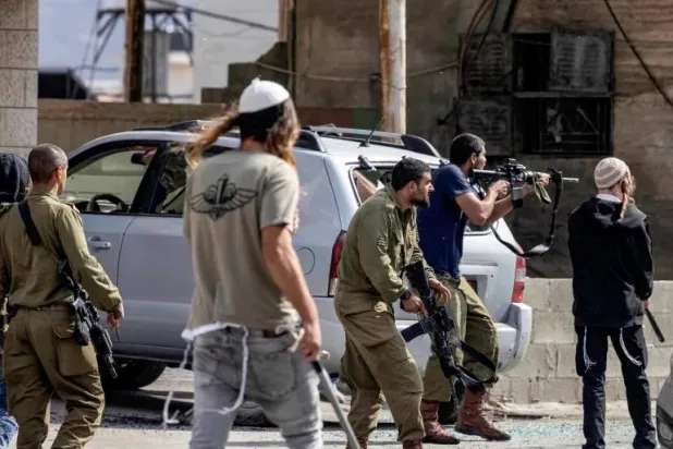مستوطنون وجنود إسرائيليون مسلّحون في بلدة حوارة بالضفة الغربية المحتلة (أرشيفية - أ.ف.ب)