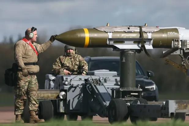 ABD askeri personeli, RAF Fairford'da bir B-1 Lancer bombardıman uçağından mühimmatı çıkarıyor (Arşiv- AFP)