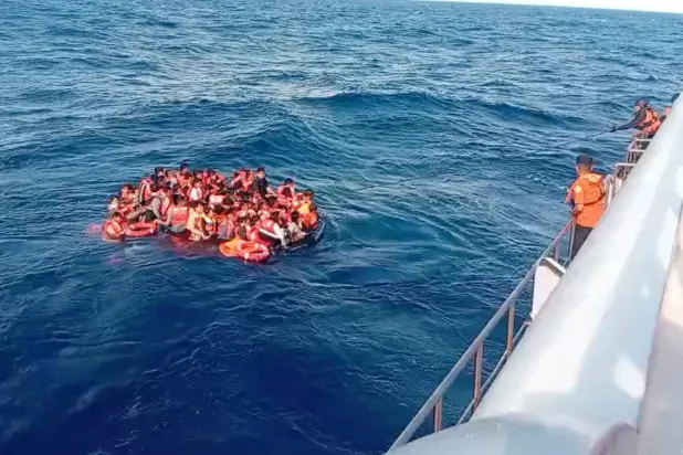 In this photo made from video released by the Indonesian National Search and Rescue Agency (BASARNAS), crew pull survivors from a passenger ferry Putri Yasmin that caught fire while traveling from the tourist island of Bali to neighboring island of Lombok toward a rescue ship in the waters of Lombok Strait, Indonesia, Wednesday, Aug. 12, 2026. (BASARNAS via AP) 