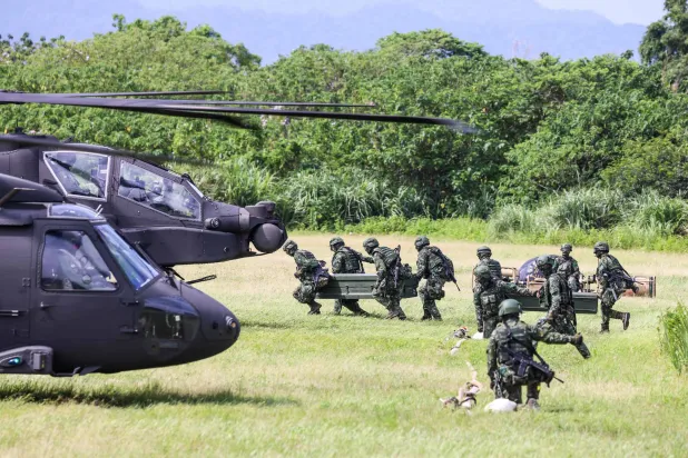Taiwanese soldiers carry fuel supplies towards AH-64E Apache Guardian and UH-60M Black Hawk helicopters during a refueling drill as part of the annual Han Kuang military exercise in Taoyuan on August 11, 2026. (AFP)