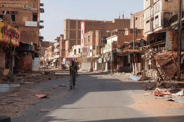 أحد أفراد الجيش السوداني يمرّ بين منازل متضررة جراء الحرب بالخرطوم (أرشيفية-رويترز)