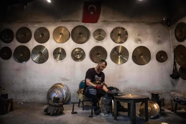 A worker hammers a cymbal at a workshop in Istanbul on July 30, 2026. (AFP) 