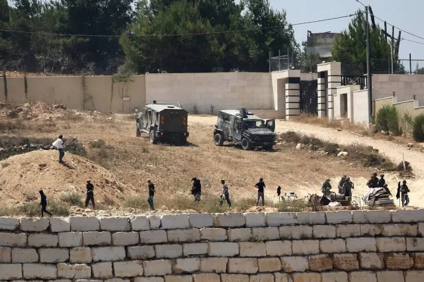  Israeli soldiers stand guard next to settlers in front of Palestinian homes that they have blockaded in the village of Qusra, south of Nablus, in the occupied West Bank, Wednesday, Aug. 12, 2026. (AP) 