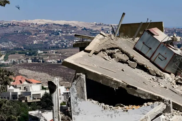 Rubble of homes in the town of Mayfadoun, with traces of a large explosion that struck in southern Lebanon seen in the background (Asharq Al-Awsat)